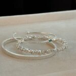 Multi-layered silver bracelet featuring vertical stripes and blue zirconia stones